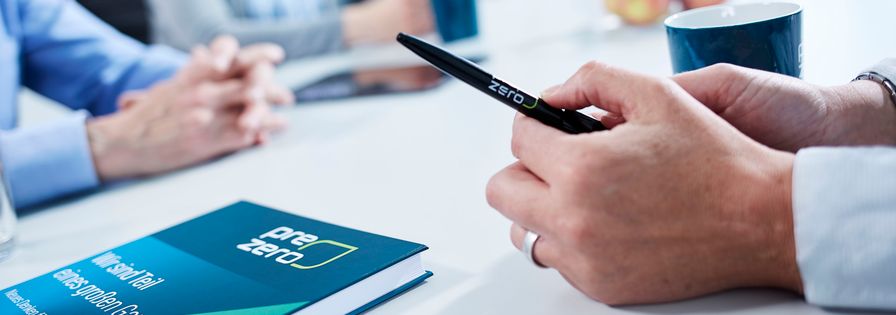 In the foreground is a PreZero pen and book. In the background you can see a discussion group