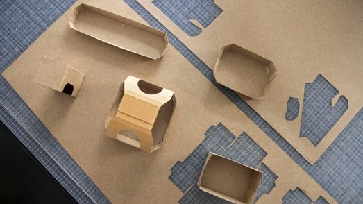 Zu sehen sind braune Faltschachteln aus Silphie-Papier auf einem Tisch aus der Vogelperspektive