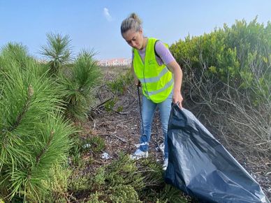 Colaboradora PreZero Portugal a recolher resíduos da praia, no dia do World Cleanup Day