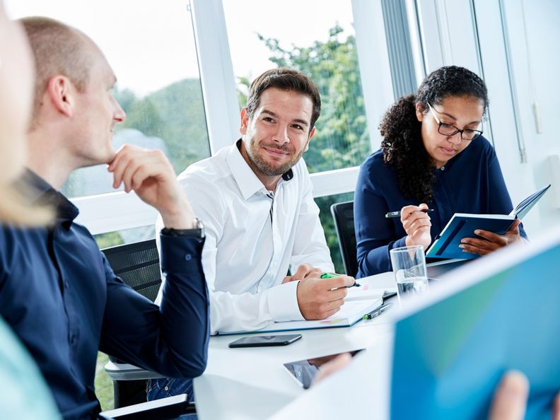 Four employees discussing in a meeting room and on the table PreZero cup